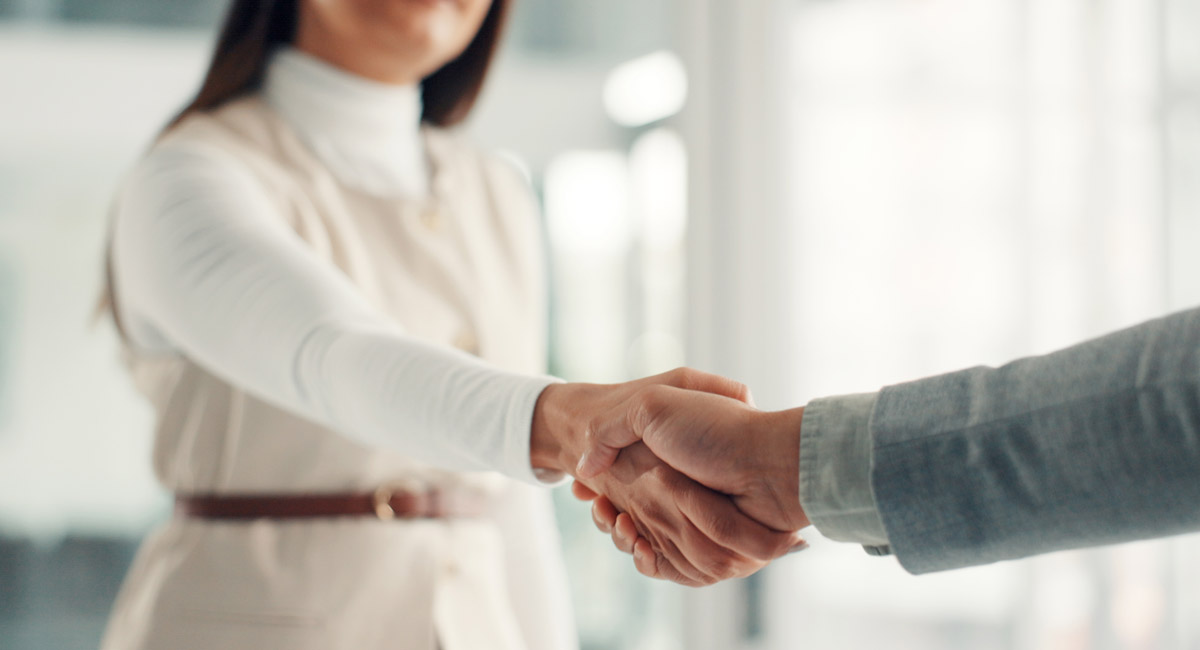 Close up of handshake between two people in office