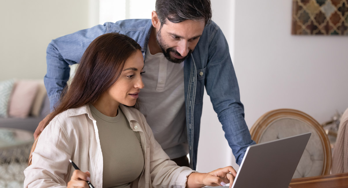 Couple reviewing laptop together while taking notes