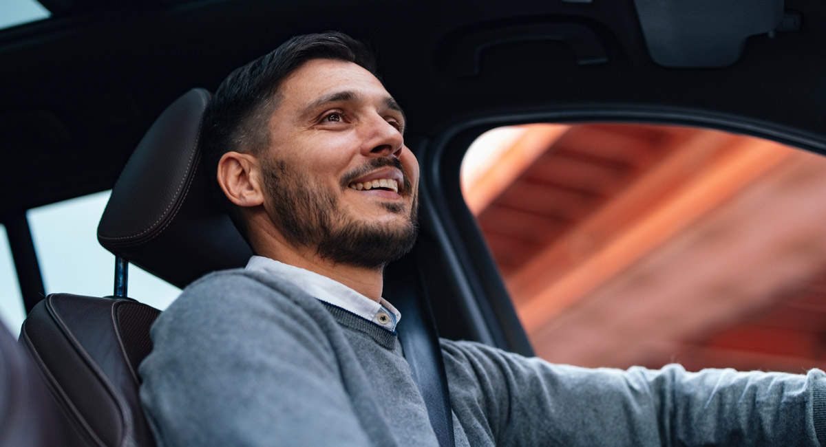 Man driving car and smiling upward