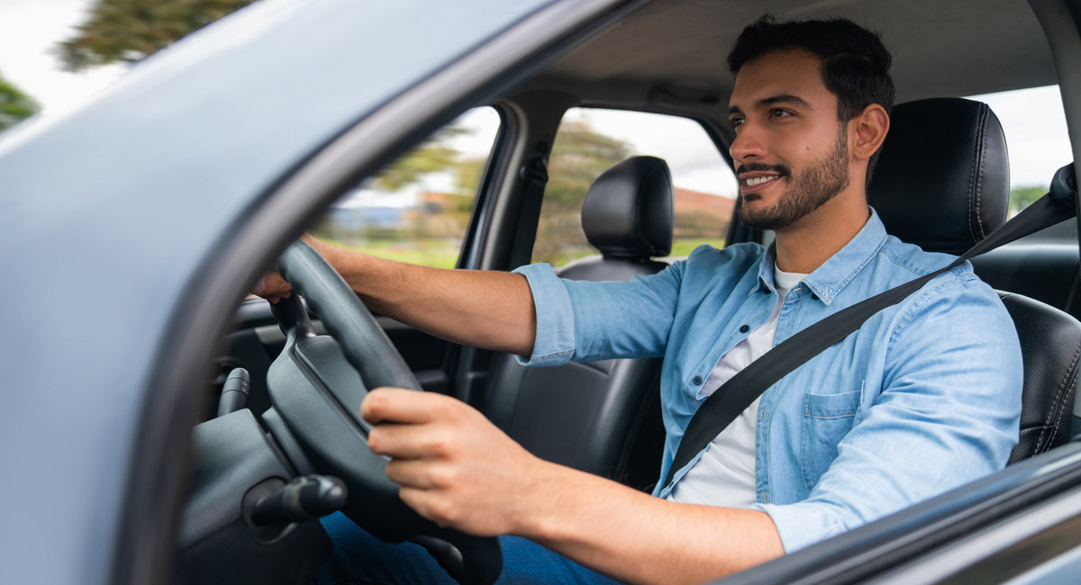 Man driving car with hands on wheel and smiling
