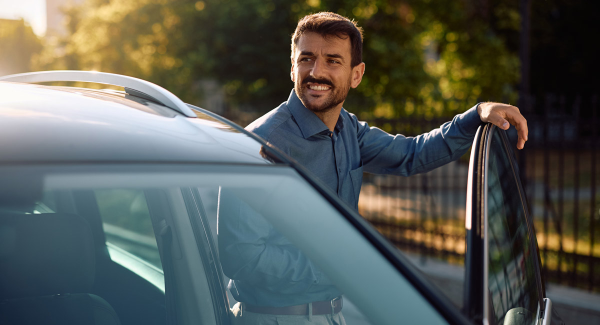 Man leaning on open car door and looking to side
