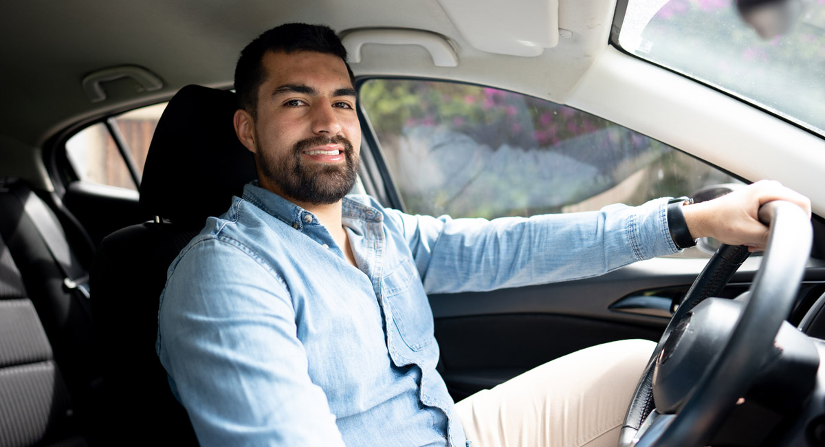 Man sitting in driver seat smiling at camera