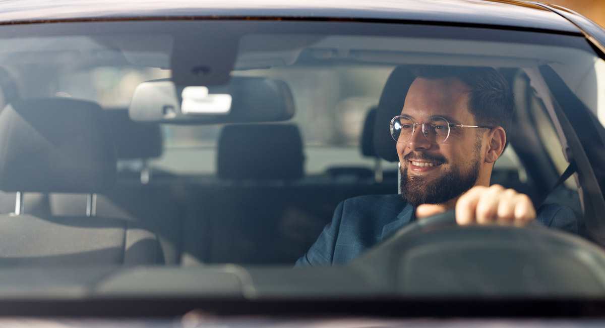 Man smiling while driving car from front view