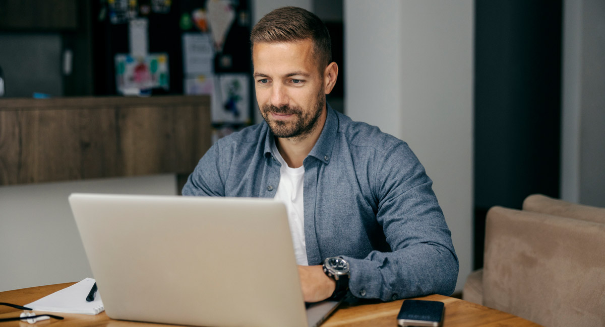 Man using laptop at table with phone nearby