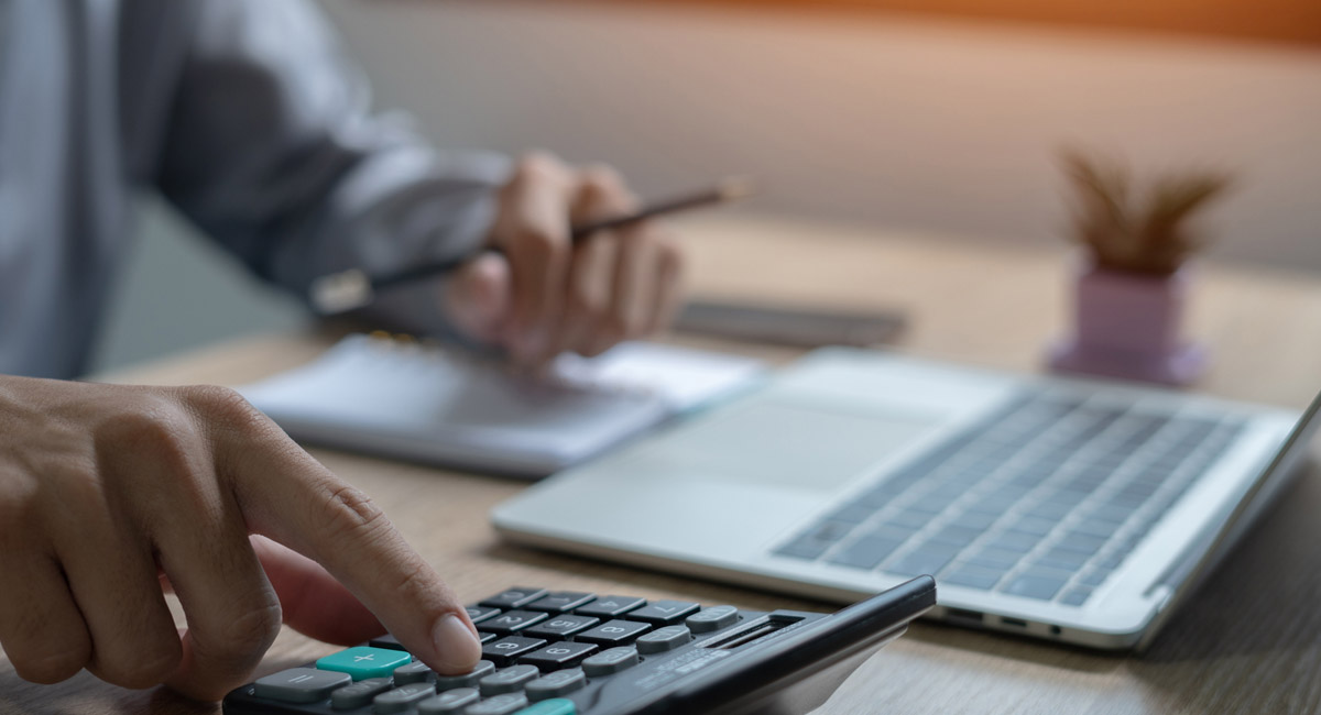 Person using calculator next to laptop and notes