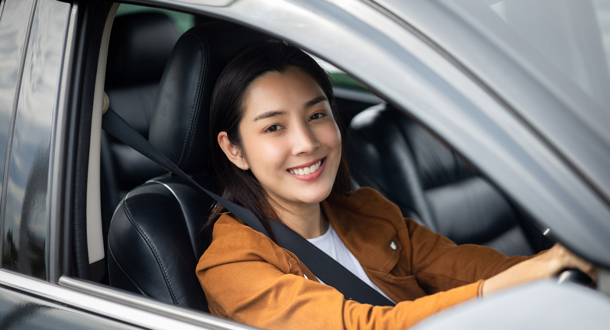 Smiling woman seated in car with seatbelt on