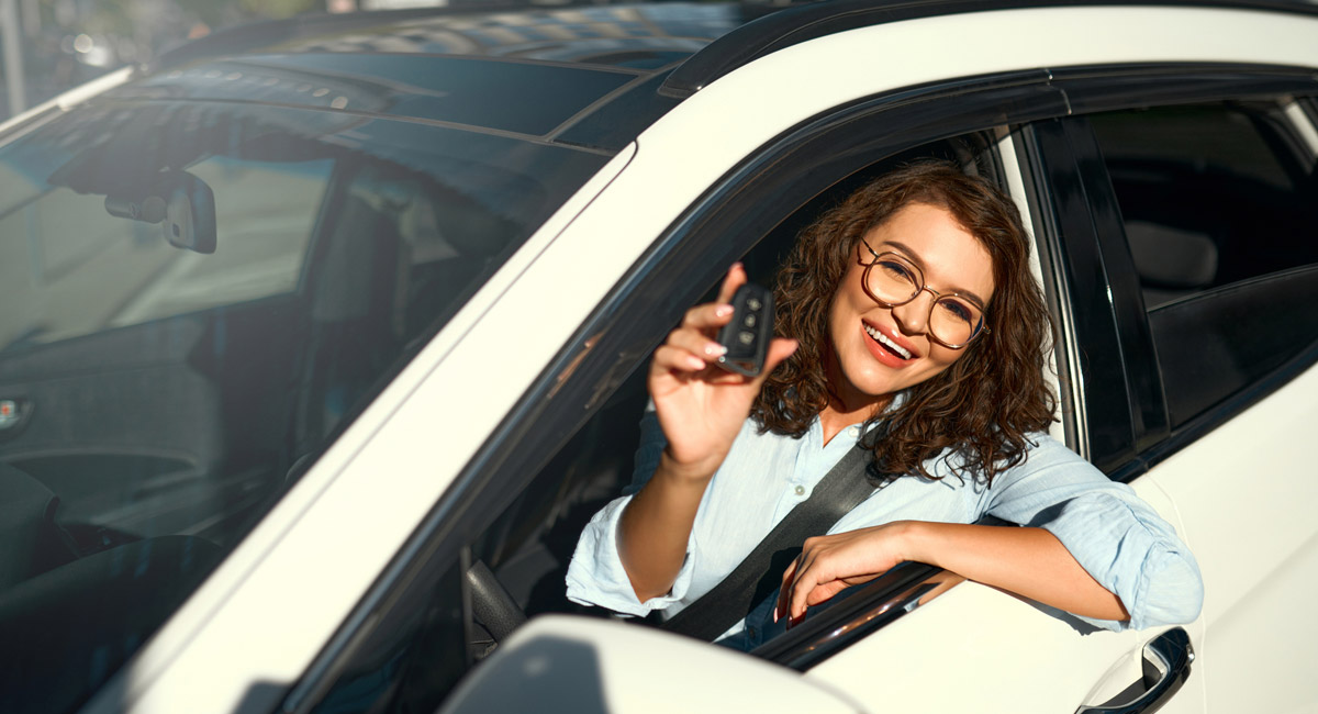 Woman in car smiling and showing keys
