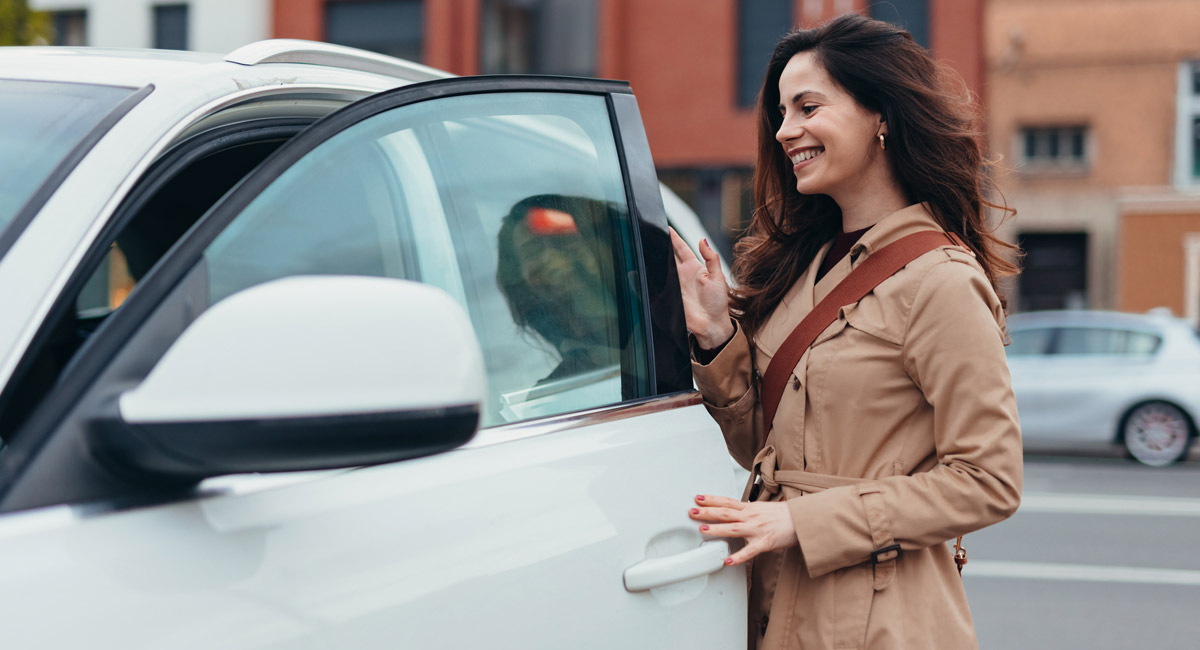 Woman opening car door and smiling