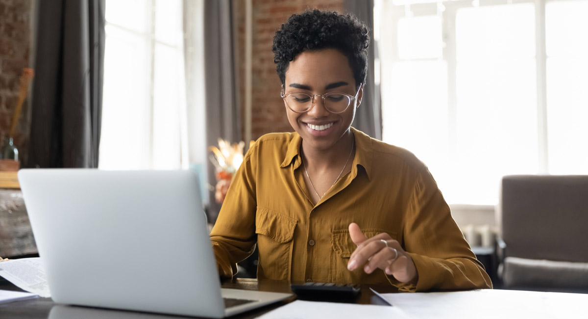 Woman smiling while using laptop and calculator