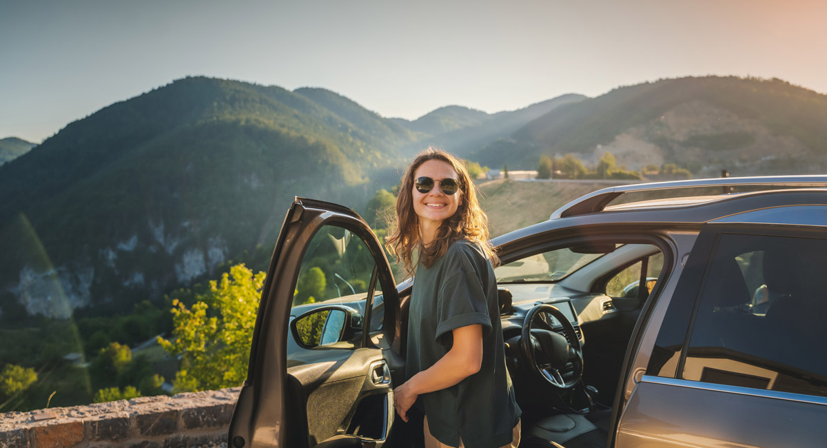 Woman stepping out of car with mountain view behind