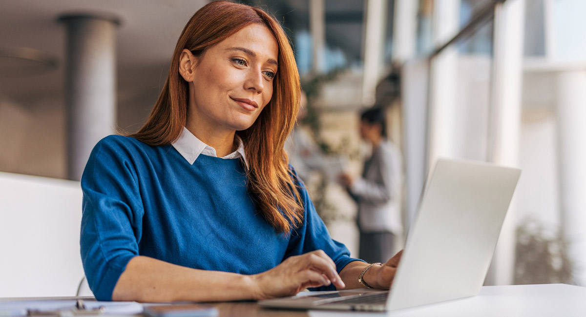 Woman typing on laptop at desk in office setting