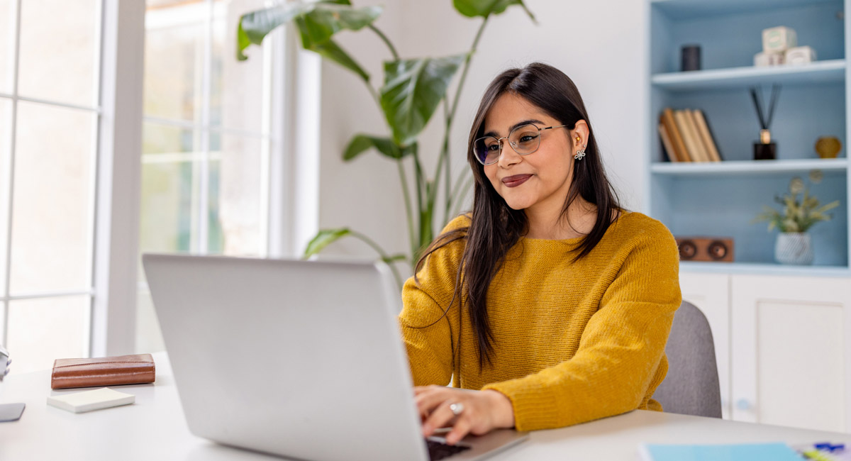 Woman working on laptop at desk and smiling