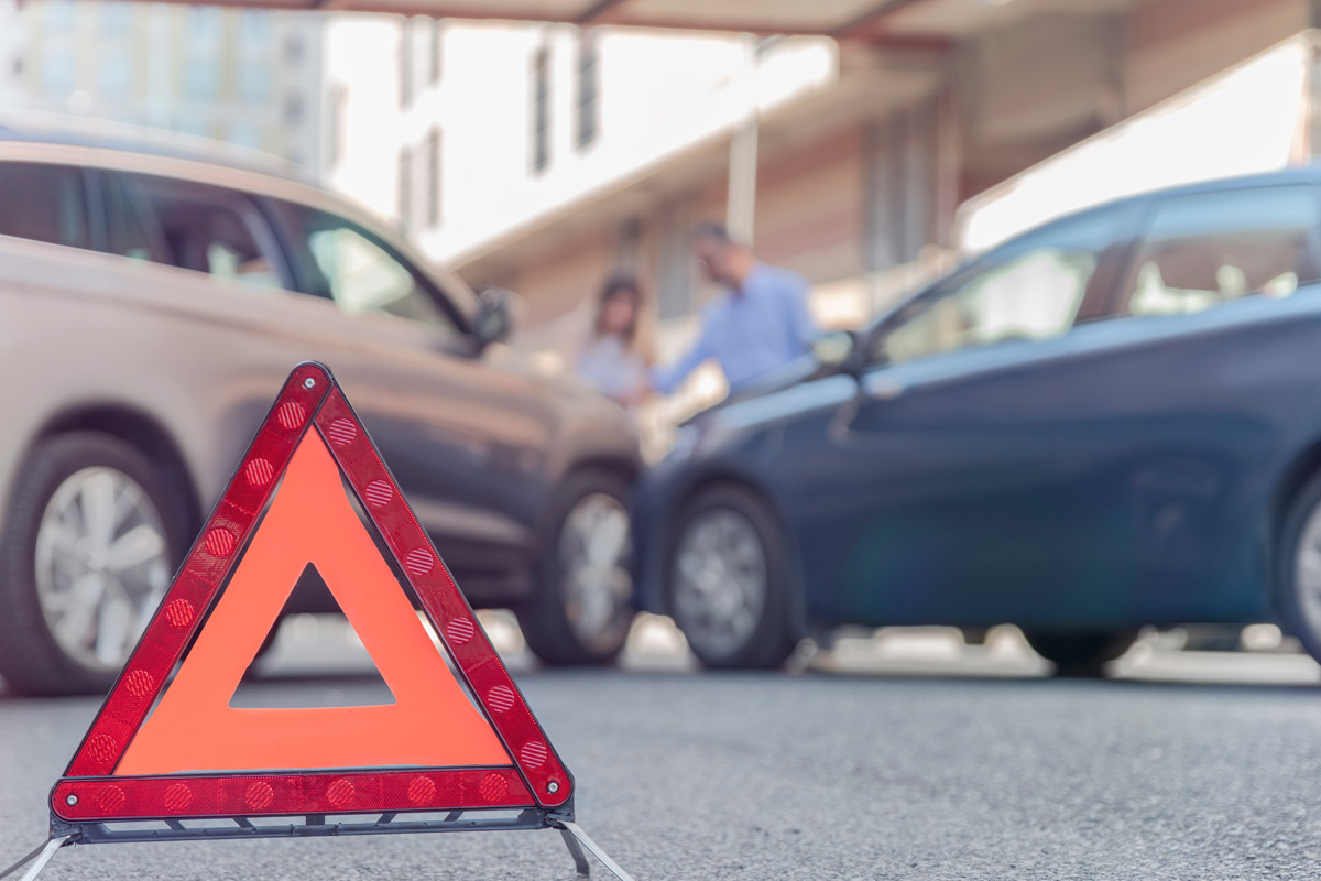 warning-sign-in-foreground-with-minor-car-accident-in-background