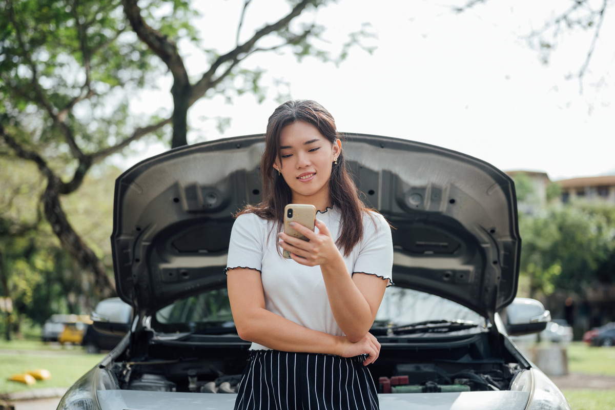 woman-on-phone-in-front-of-car-with-raised-hood