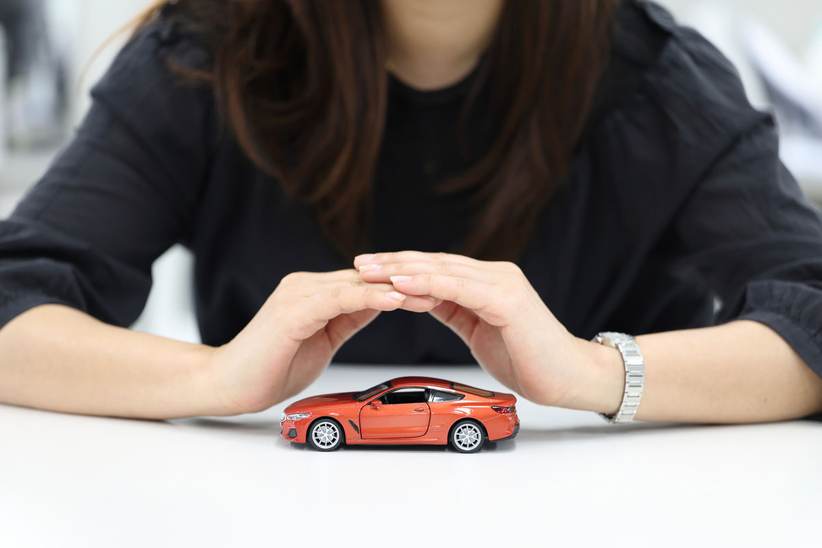 woman-at-table-with-hands-over-red-model-car
