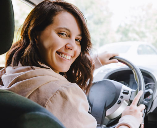 smiling-woman-in-the-driver's-seat-looking-over-her-shoulder