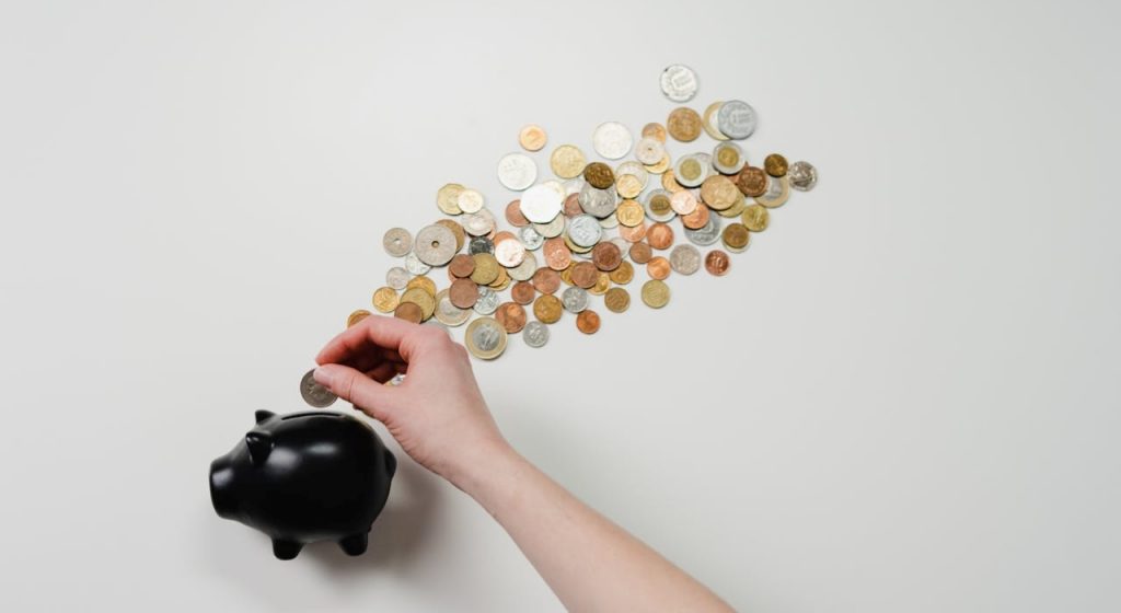 hand putting coins in a black piggy bank