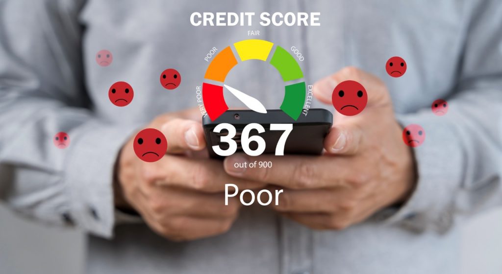 Person holding a smartphone with bad credit score meter on the screen