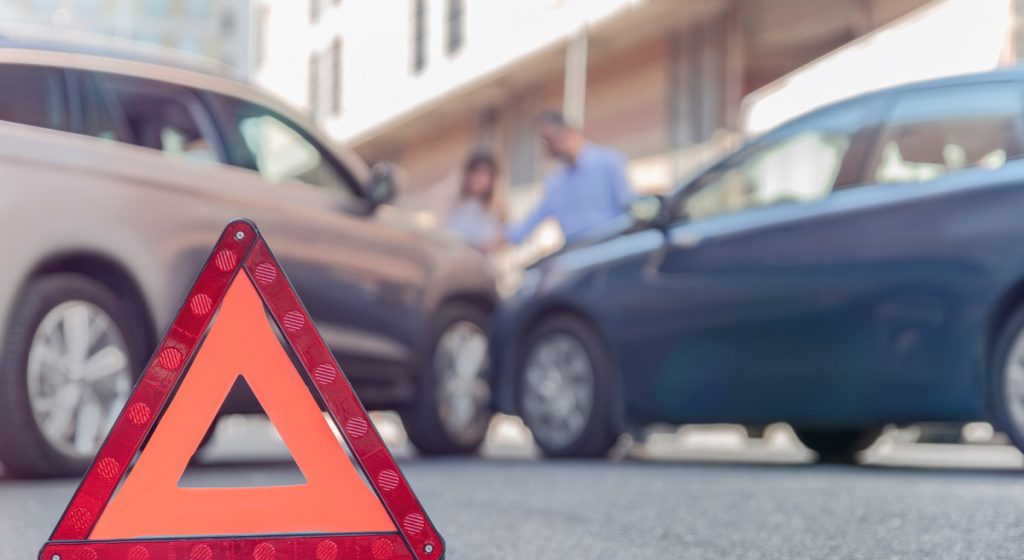warning-sign-in-foreground-with-minor-car-accident-in-background