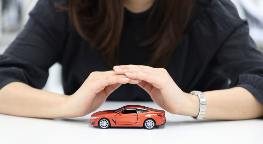 woman-at-table-with-hands-over-red-model-car