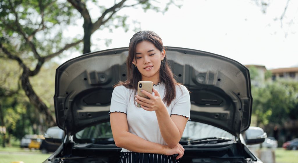 woman-on-phone-in-front-of-car-with-raised-hood
